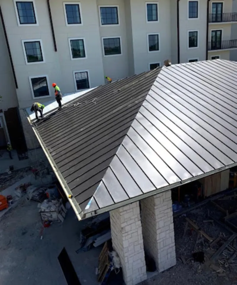Crew installing standing seam metal roof panels on a commercial project in Redland